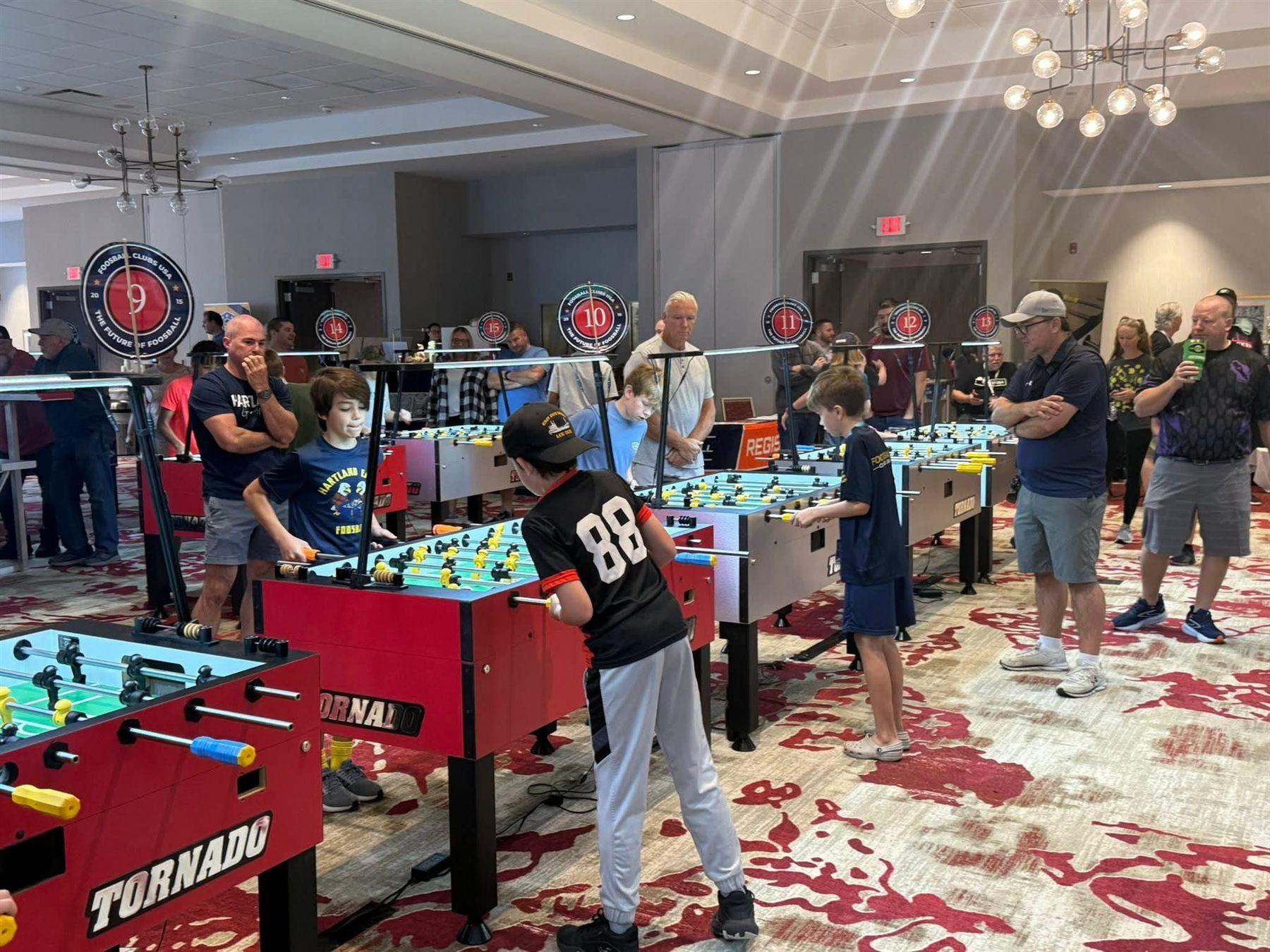 The full tournament ballroom at the 2025 Great Lakes Classic, with rows of Tornado tables, students playing, and families watching